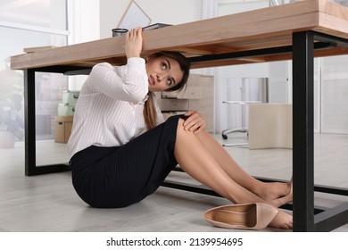 Scared Young Woman Hiding Under Office Desk During Earthquake