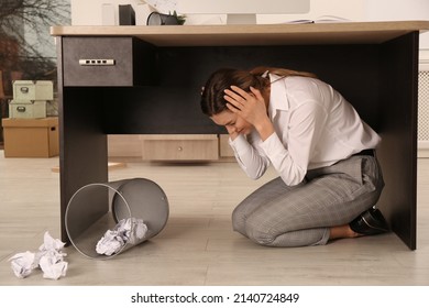 Scared Young Woman Hiding Under Office Desk During Earthquake