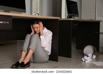 Scared Young Woman Hiding Under Office Desk During Earthquake