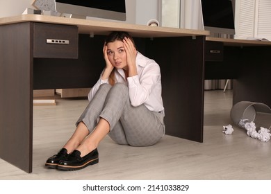 Scared Young Woman Hiding Under Office Desk During Earthquake