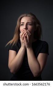 Scared young woman in studio on gray background