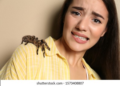 Scared Young Woman With Tarantula On Beige Background. Arachnophobia (fear Of Spiders)