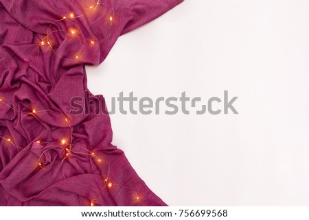 Scarf and Christmas lights on white background. Top view