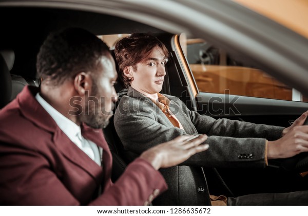 Scarred man. Young dark-eyed man feeling\
a little bit scarred while learning\
driving