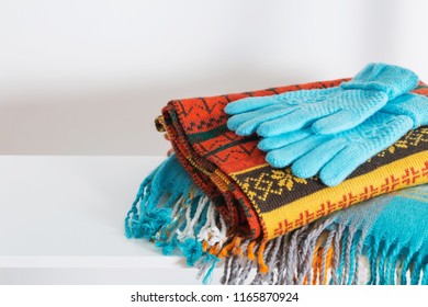 scarves and gloves on white wooden shelf