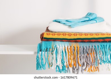 scarves and gloves on white wooden shelf