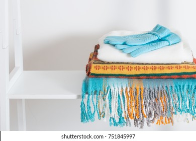 scarves and gloves on white wooden shelf