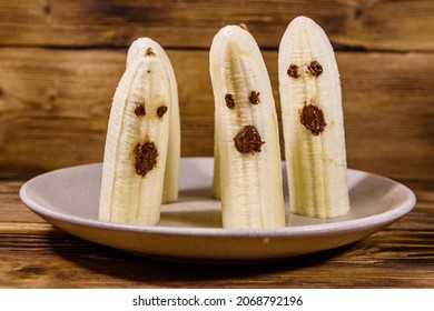 Scary Banana Ghosts In Ceramic Plate On Wooden Table. Halloween Concept