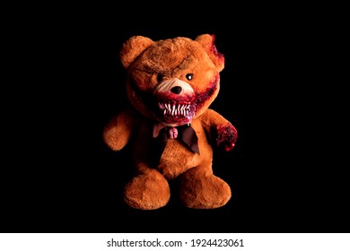 scary bear with a creepy bloody grin on a black background. horror toy. halloween concept. a severed paw and a bitten off ear covered in blood