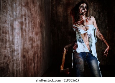 Scary bloody zombie girl with an ax. Halloween.
