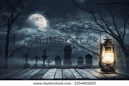 Scary cemetery with ancient graves and old lit lantern in the foreground