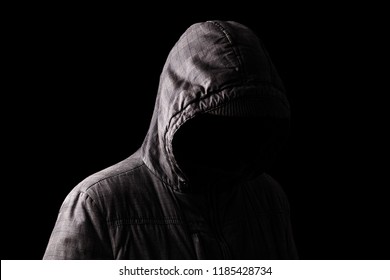 Scary And Creepy Man Hiding In The Shadows, With The Face And Identity Hidden With The Hood, And Standing In The Darkness. Low Key, Black Background. Concept For Fear, Mystery, Danger, Crime, Stalker