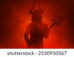 Scary devil silhouette holding pitchfork trident in hell with smoke mist fog, Halloween theme