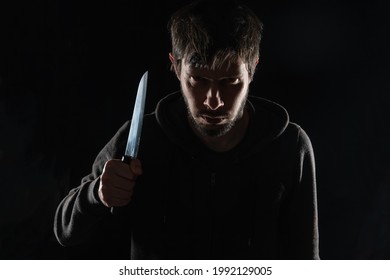 Scary and evil maniac or murderer with knife on black background.