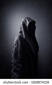 Scary figure in hooded cloak in the dark. - Shutterstock ID 1828874228