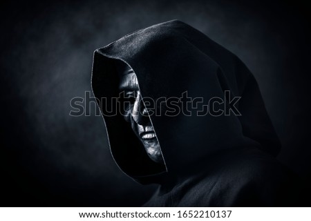 Scary figure in hooded cloak with mask