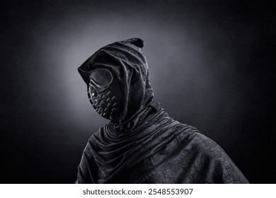 Scary figure in hooded cloak with spike studs mask at night over dark misty background - Powered by Shutterstock