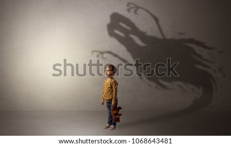 Scary ghost shadow in a dark empty room with a cute blond child
