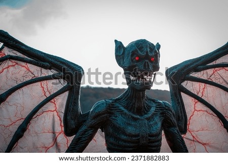 scary halloween monster statue wings with red veins red eyes on sky background seasonal decorations