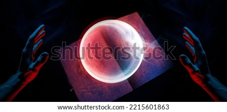 A scary hand over magic book on dark background. Mysterious composition. Fortune teller, mind power, prediction, halloween concept. Wide angle horizontal wallpaper or web banner. 