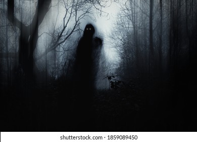 A scary hooded figure with glowing eyes in a spooky forest on a foggy winters day. With a artistic, blurred, abstract, grunge edit.