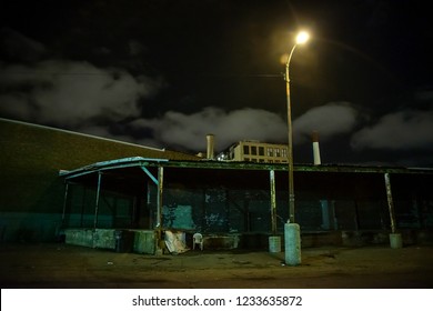 Scary industrial urban street city night scene with decaying loading docks by vintage factory warehouses - Powered by Shutterstock