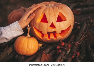 Scary Jack O Lantern Halloween Pumpkins In Sun Day On Ground Among Dry Leaves At Street. Hallows Eve Decoration Funny Glow Pumpkin With Candles On Candlestick At Fall Background In Open Air Near House