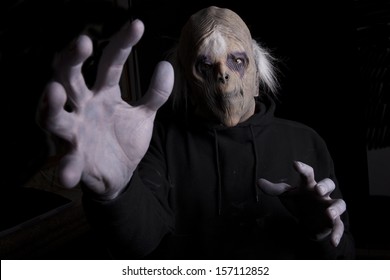 A Scary Looking Zombie Reaching Forward To Grab Someone With His Hand Out Stretched, Dark Background.