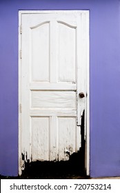 Scary Old Broken Wooden White Door And Purple Color Wall. Concept For Dirty, Destroyed, Abandoned.