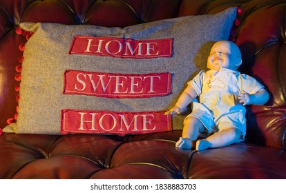 Scary Porcelain Doll On A Red Leather Sofa Next To A Home Sweet Home Cushion 