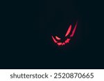 A scary red smile from demon in a dark background. Halloween theme.