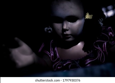 A Scary And Sinister Looking Doll Comes Out From The Dark And Climbs The Bed. Ominous Black Eyes And Expressionless Face. Horror Or Disturbing Concept In Bedroom.