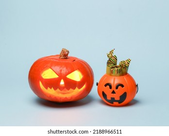 Scary Smiling Halloween Jack Lantern Pumpkin Head With Burning Candle And Halloween Candy Bucket On Blue Background