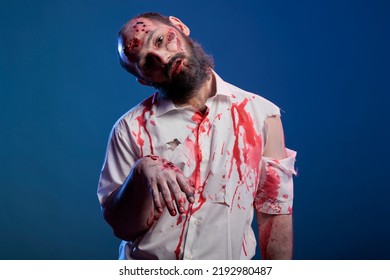 Scary Undead Zombie Looking Crazy Evil, Having Blood On Shirt And Dangerous Aggressive Bloody Look. Eerie Apocalyptic Corpse With Ugly Dirty Scars And Wounds, Brain Eating Demon.