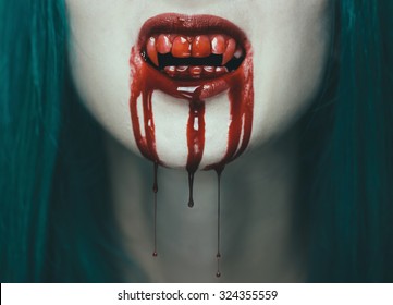 Scary vampire woman, close-up of mouth with teeth in blood. Halloween or horror theme