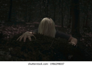 Scary Woman Crawling On The Forest Floor In Dark, Coming Up Behind Tree Trunk, Hand Reaching Forward