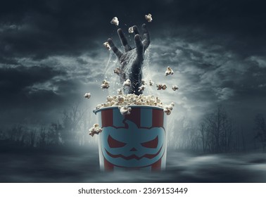 Scary zombie hand coming out of a popcorn bucket: horror movies and Halloween concept