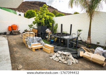 Scattered construction site materials and tools in backyard. Construction work beginning early stage ready for garden backyard renovation