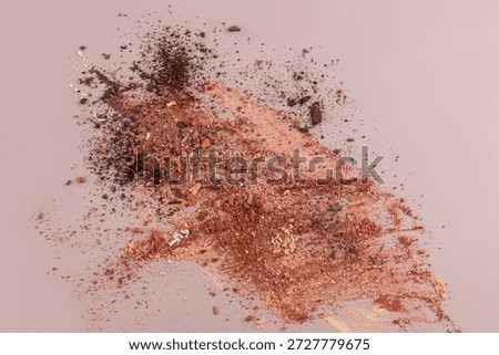A scattered dry mixture of textures in different shades of brown eyeshadow on a beige background. The concept decorative cosmetics. view. copy space