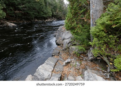scattered gray boulders resting by the deep blue water in the parc des chutes dorwin