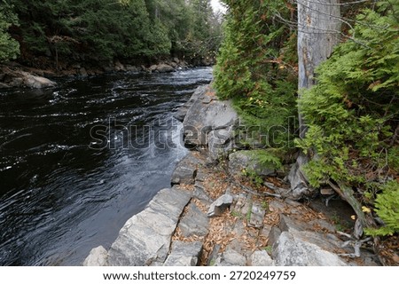 scattered gray boulders resting by the deep blue water in the parc des chutes dorwin