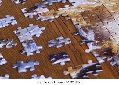 Scattered Pieces Of Jigsaw Puzzle On Wooden Table. Effort To Fit Thing Together.