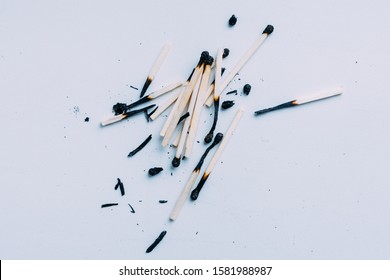 Scattered pile of extinguished
burned matches on white surface.