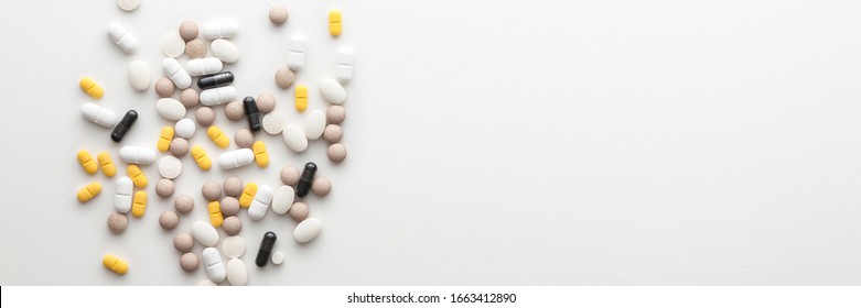 Scattered pills on a white wooden table. Copy space. Pharmacy and pharmacology. Top view. Panoramic photo - Shutterstock ID 1663412890
