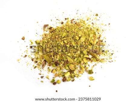 Scattered pistachio nut pieces isolated. Break chopped pistachios pile, fried baked diced pistache on white background 