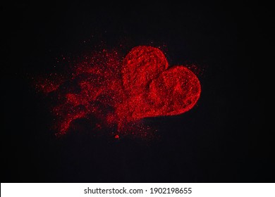 Scattered red heart made of sparkles on a black background. Shimmering dust symbol. Broken love concept