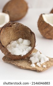 Scattered Scrub In Coconut On White Background. Home Spa Treatment Concept, Organic Cosmetic. Vertical Photo.