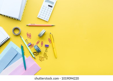 Scattered stationery on student's desk. Yellow background top view copy space - Shutterstock ID 1019094220