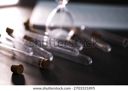 Scattered Test Tubes with Sand Timer on Dark Surface Representing Time and Science in Focus