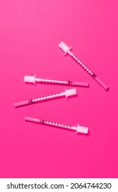 Scattered thin cosmetic syringes on pink background. Cosmetology and beauty industry
